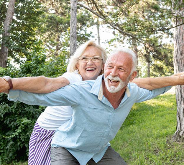 An older man and his wife acting playful outdoors